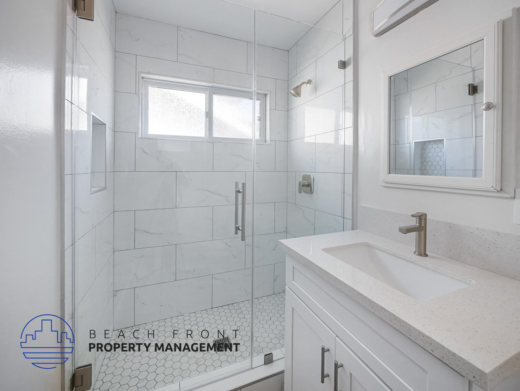 A white bathroom with a sink and a shower.